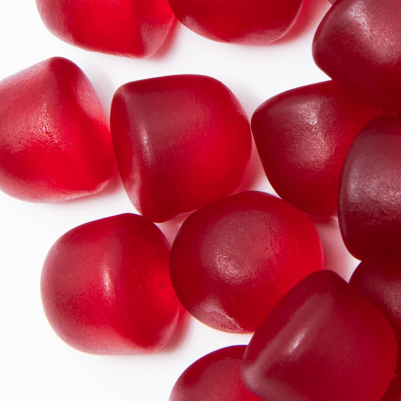 Alfa Vitamins Fiber Gummies - 60 Gummies are scattered on a white background, exuding a smooth texture and slightly irregular shapes with a shiny allure. Infused with prebiotic fiber, these gummies delight your taste buds while supporting gut health.