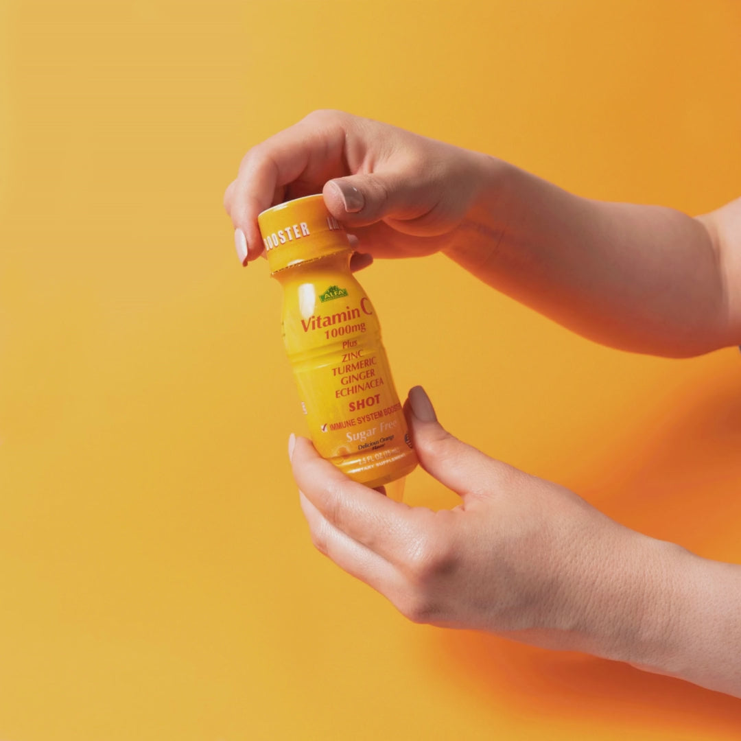 Video of a hand opening a vitamin c shot  on a yellow orange background