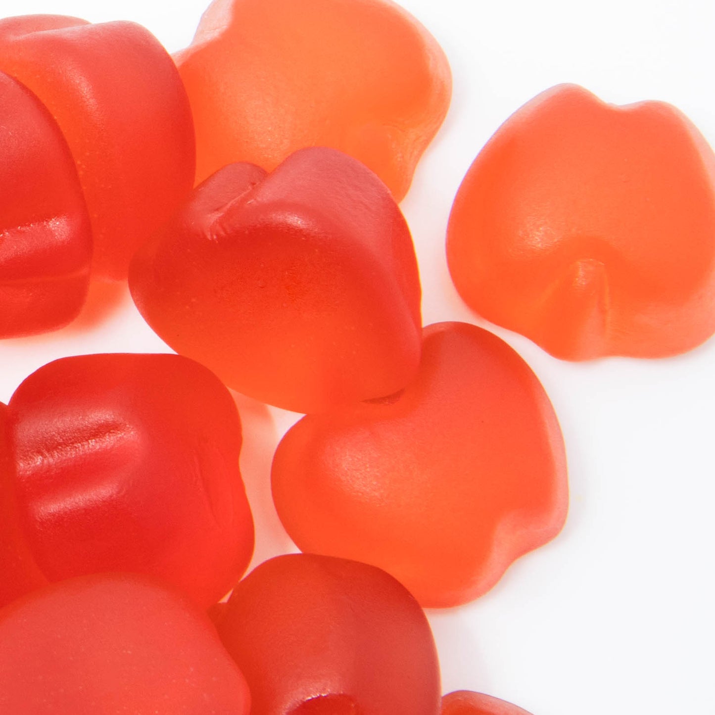 A close-up of assorted orange and red gummy candies, resembling Alfa Vitamins Stores Apple Cider Vinegar Gummies with Vitamin B12, heart-shaped and artfully displayed against a pristine white background.