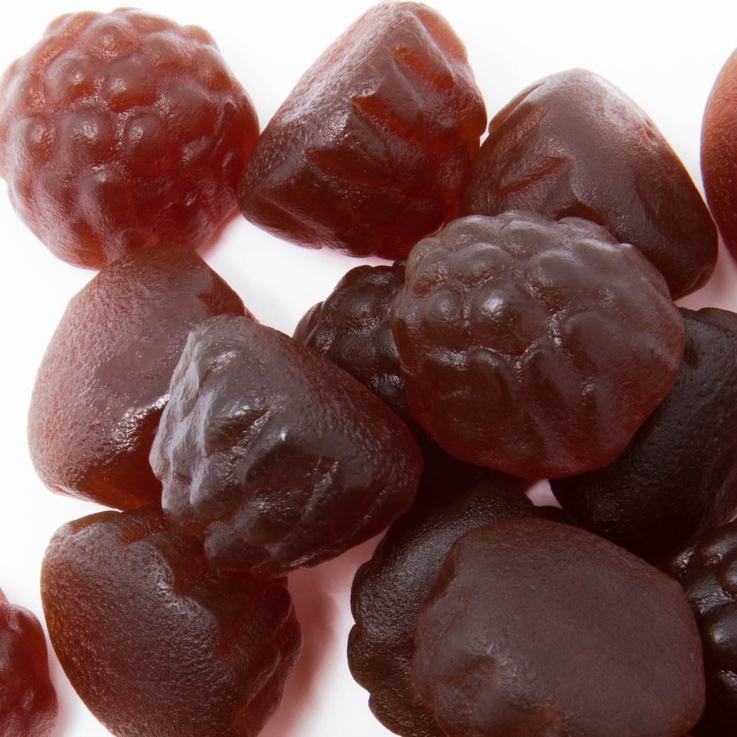 Close-up of assorted dark-colored Alfa Vitamins ELDERBERRY + C & ZINC gummies, shaped like berries and infused with elderberry extract for a tart twist. Their shiny texture is eye-catching as they cluster together on a white background.