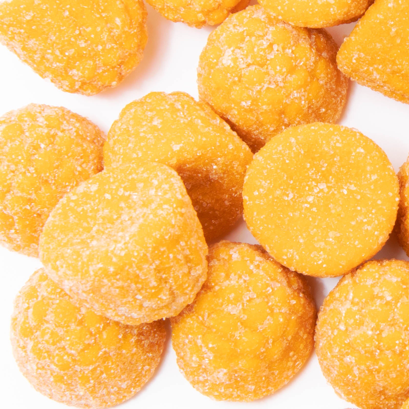 A close-up shows multiple bright yellow, sugar-coated Turmeric Ginger Gummies from Alfa Vitamins Store arranged on a white surface. The gummies have a round, slightly irregular shape and a textured surface.