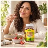 An adult holding a B Complex gummy at a breakfast table.