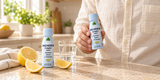 Alfa Magnesium Complex Shot with lemon — hand holding a shot beside a kitchen counter.