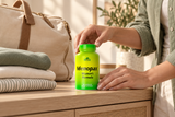 An adult hand with Menopax Women's Formula - 100 capsules beside everyday belongings.