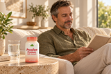 An adult man reads in a sunlit room with Prosfen Premium Male Formula 120 capsules and a glass of water on a stone side table.