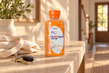 One Genesisvit Electrolyte Orange bottle from the twelve-pack on an entryway console beside a canvas tote.