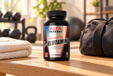 Alfa Sports Maximum L-Glutamine 1000 mg bottle, 100 capsules on a bench beside a folded towel and closed gym bag.