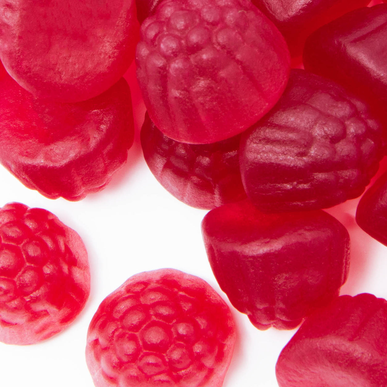 Close-up of red raspberry-shaped gummies on a white background.